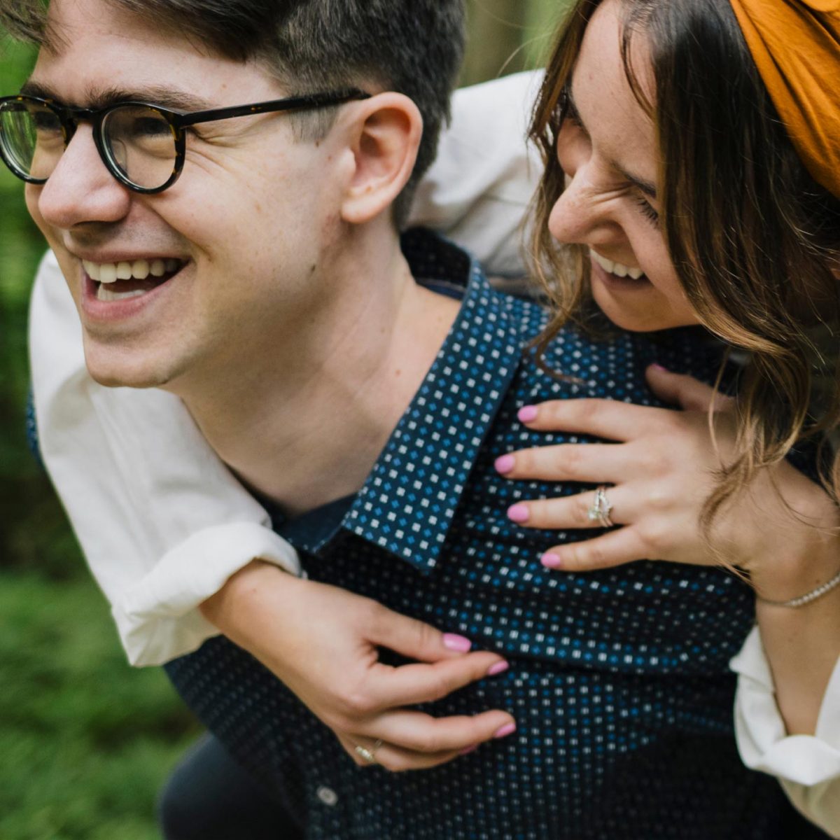 Man and woman smiling with woman getting a piggy back ride